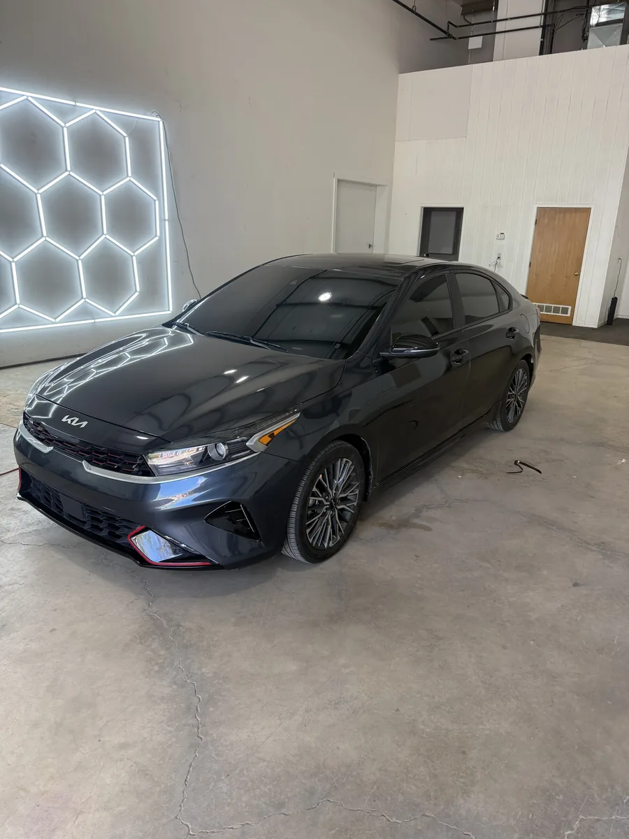 Black Kia Forte with a mirror finish under the hex lighting in the A2 Auto Works bay