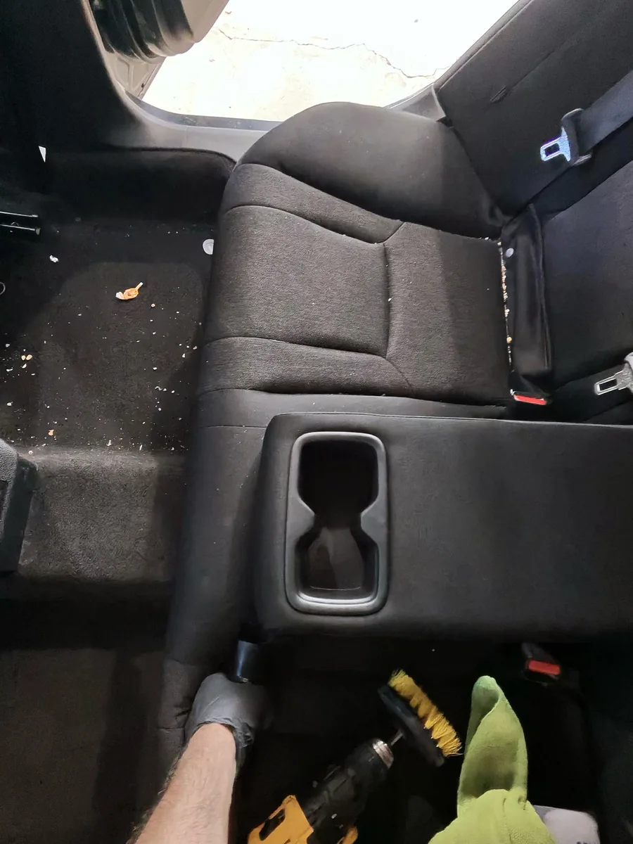Gloved hand working on a rear seat and carpet mid-detail