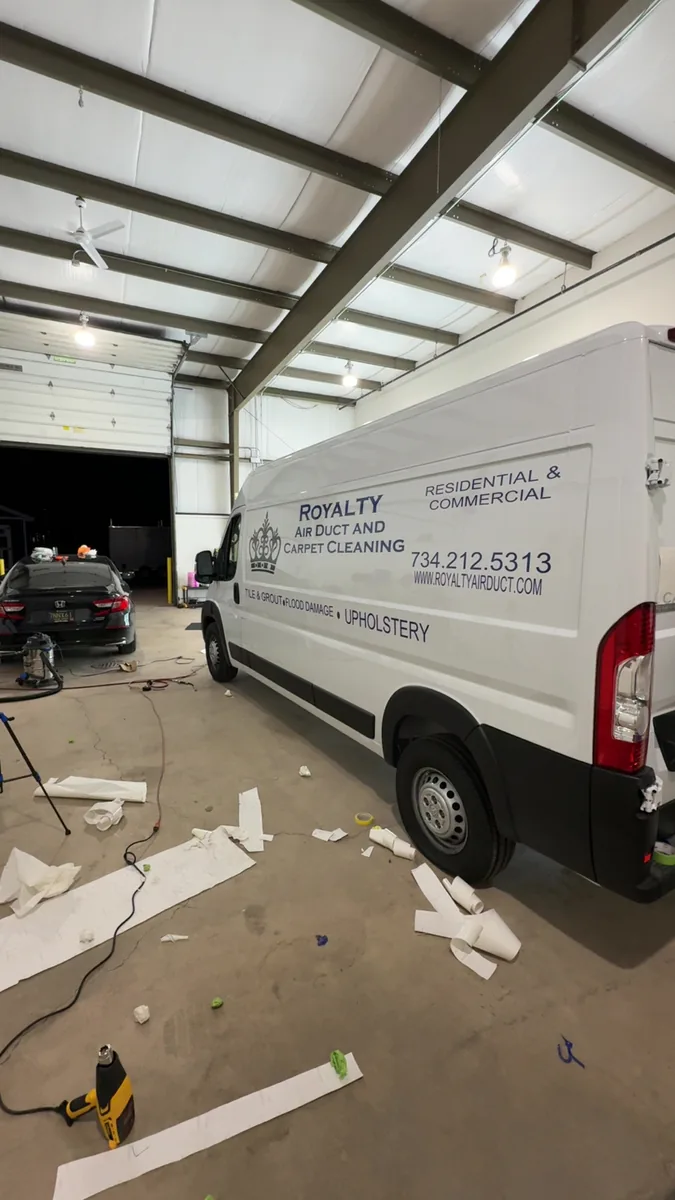 White Royalty Air Duct and Carpet Cleaning van parked inside the shop