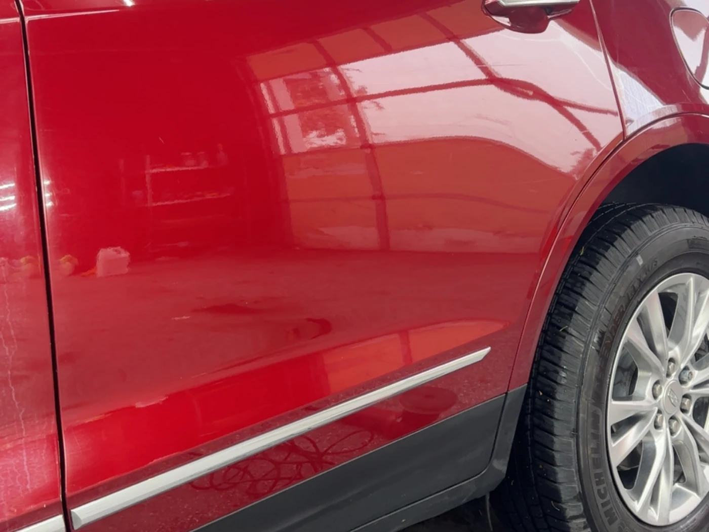 The same Cadillac door after paint correction, the reflection sharp and the swirl marks gone
