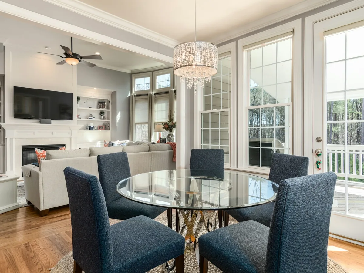 A bright living and dining room with a wall of west-facing windows and a glass door