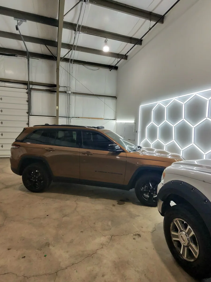 Bronze Jeep Grand Cherokee parked in the shop next to another vehicle