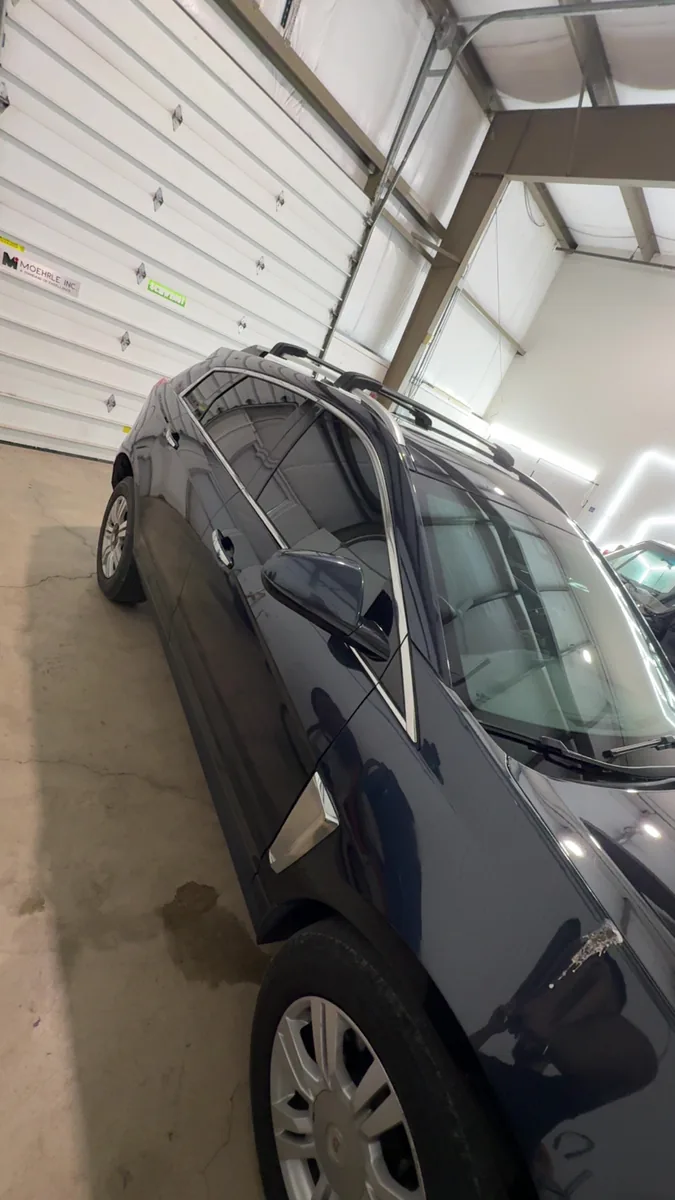 Dark blue Jeep Grand Cherokee with tinted glass inside the shop