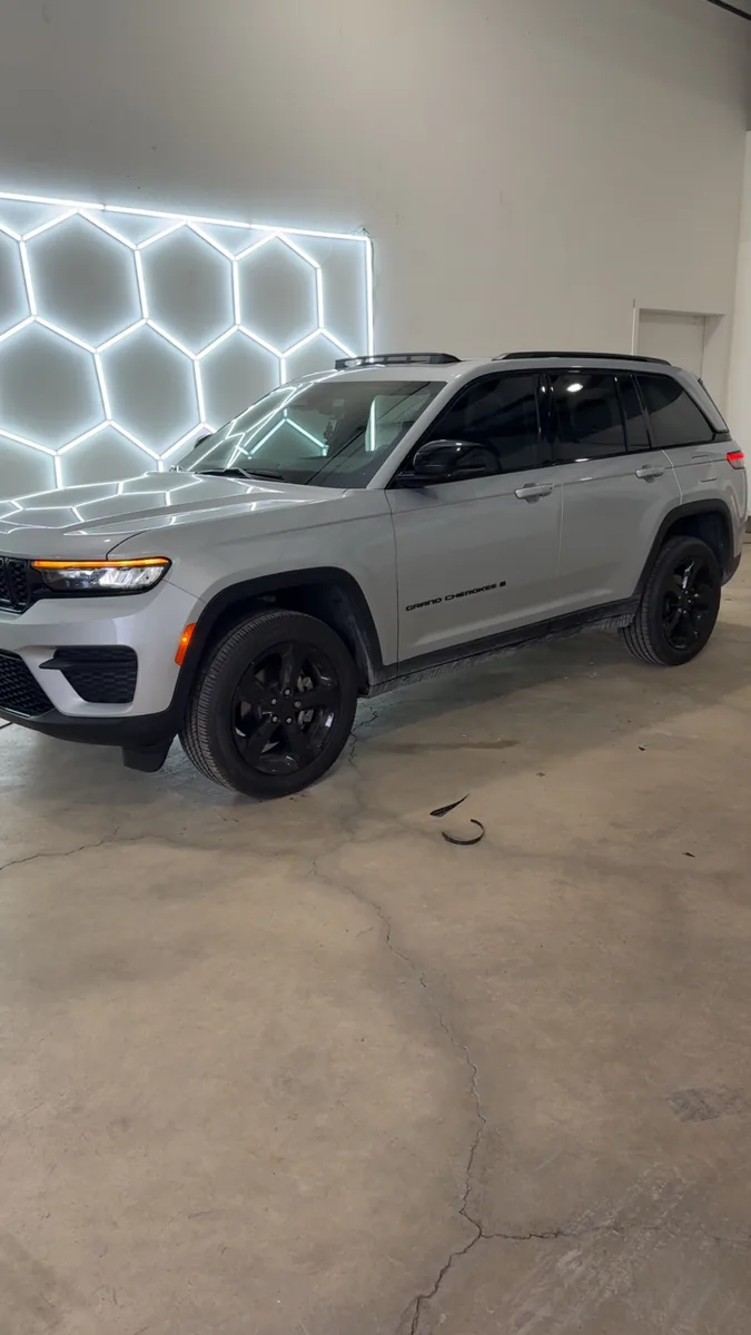 Silver Jeep Grand Cherokee with tinted windows under the shop lights