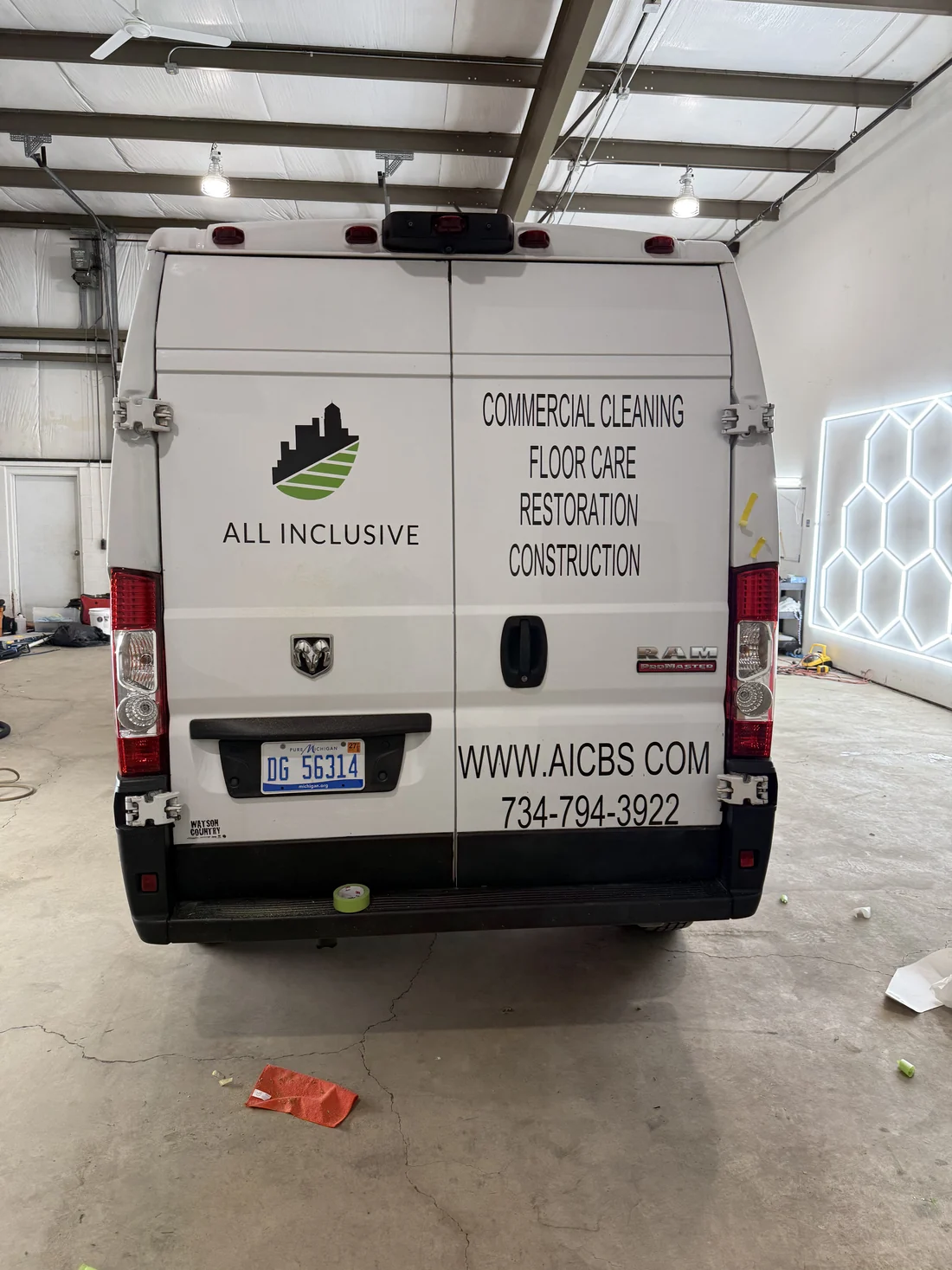 The rear doors of the same van with the company logo, service list, website and phone number applied in vinyl